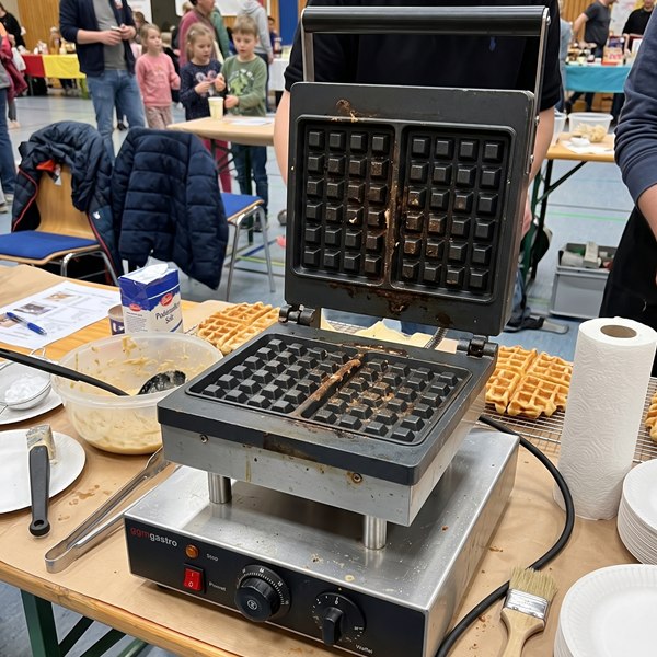 Profi-Waffeleisen für Brüsseler Waffeln im Einsatz auf einer Veranstaltung mit Waffelteig und Puderzucker